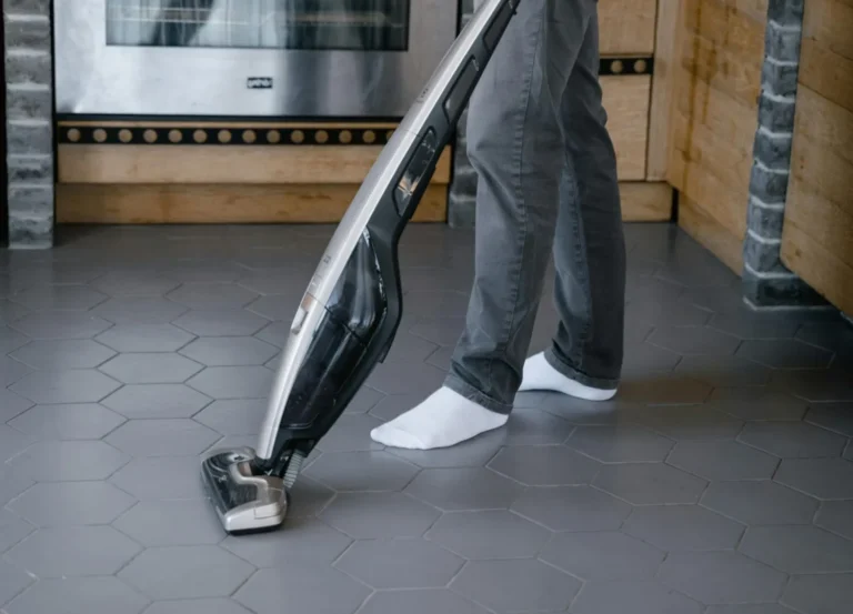 Pessoa usando um aspirador de pó em uma cozinha com piso de porcelanato.